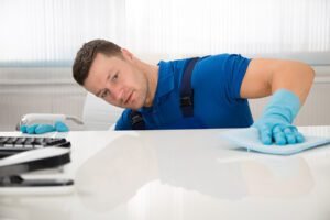 Janitor using blue cloth to clean desk