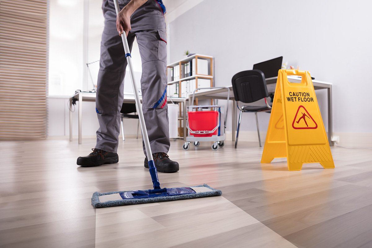 Janitor using floor mop to clean office floor